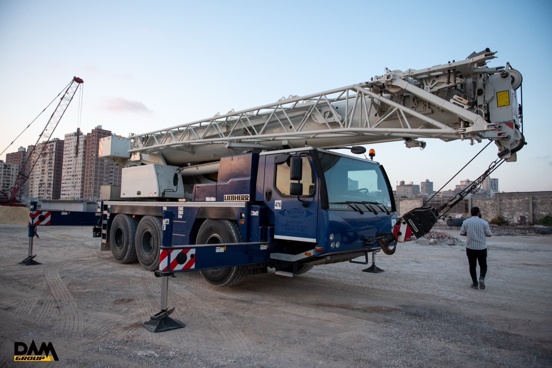 Liebherr mobile crane with its boom raised against a dusk sky